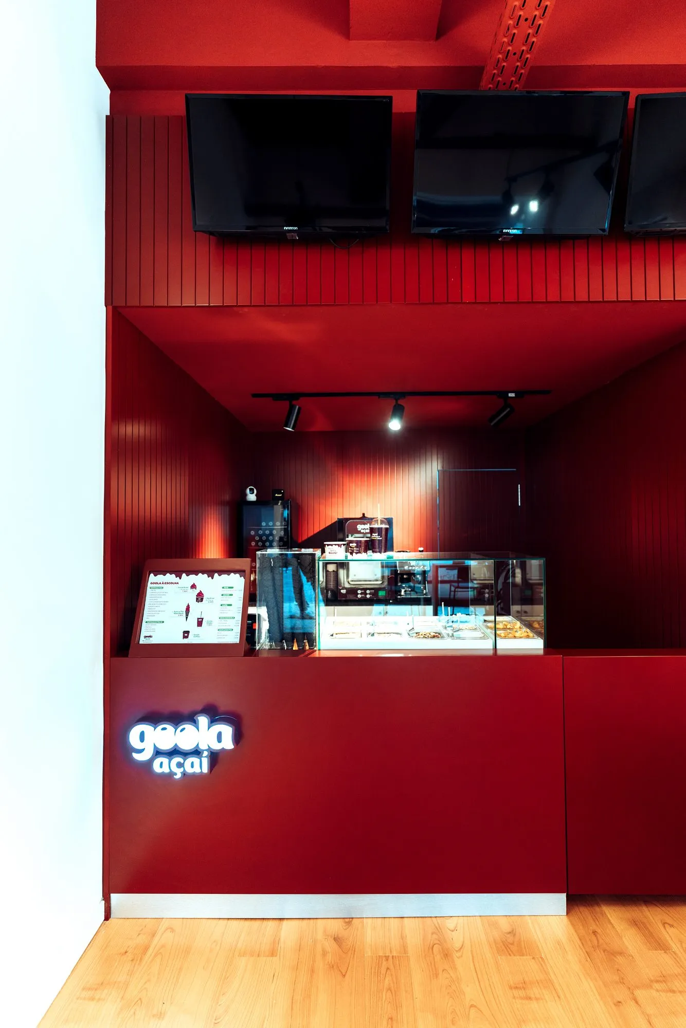 Balcão da Goola Açaí em Alvalade, em vermelho com o letreiro luminoso da marca, vitrina e ecrãs de menu por cima