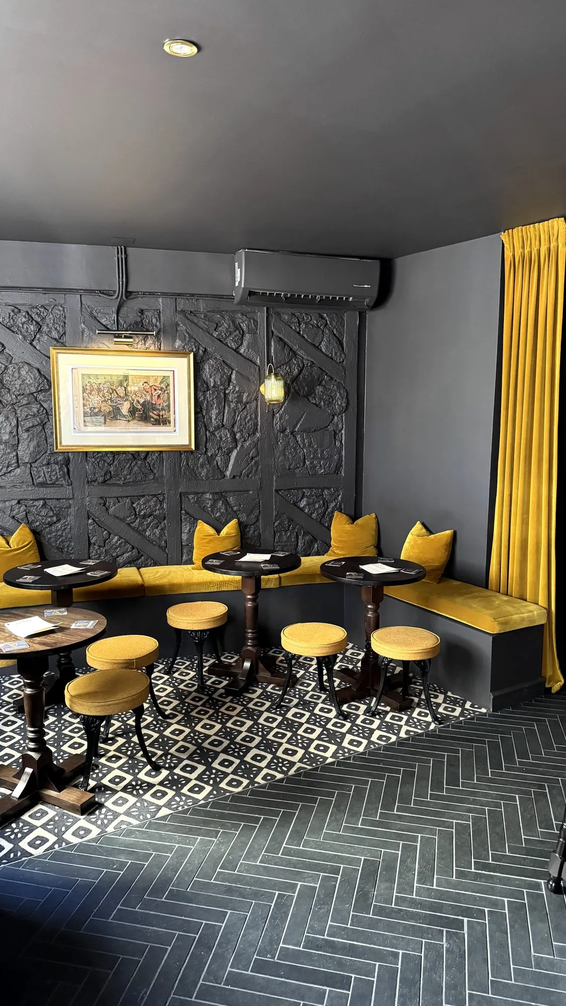 Sala com banco corrido em veludo amarelo e pavimento em espinha